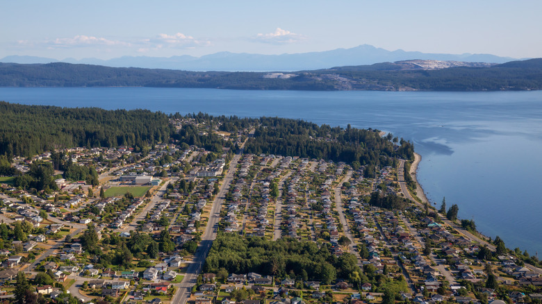 An aerial view of buildings and streets in Powell River, surrounded by mountains and forest.