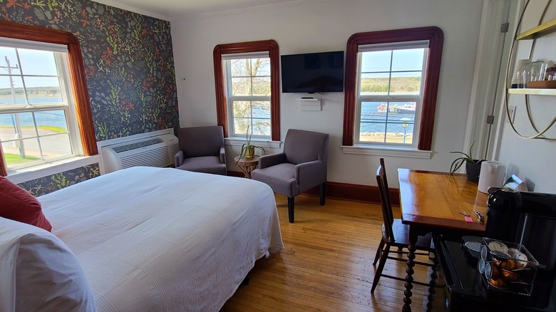 A boutique hotel room with green, leafy wallpaper and coastal views in Chéticamp, Nova Scotia