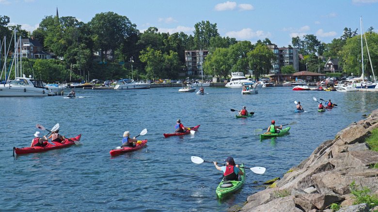 A group of kayakers on a paddle excursion among the Thousand Islands of the St. Lawrence River returns to Gananoque harbor