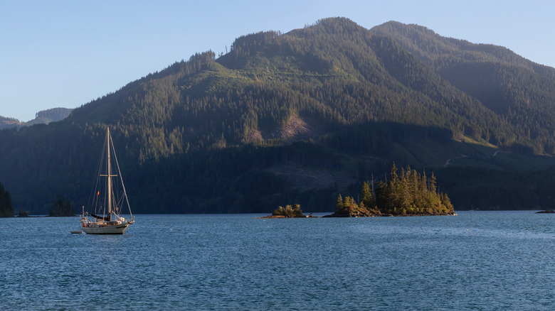 A boat sails across an inlet at sunset, with mountains and islands in the backdrop