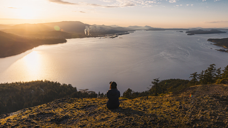A person enjoying the sunset view atop Mount Erskine in Mount Erskine Park, Salt Spring Island, South Gulf Islands, British Columbia, Canada