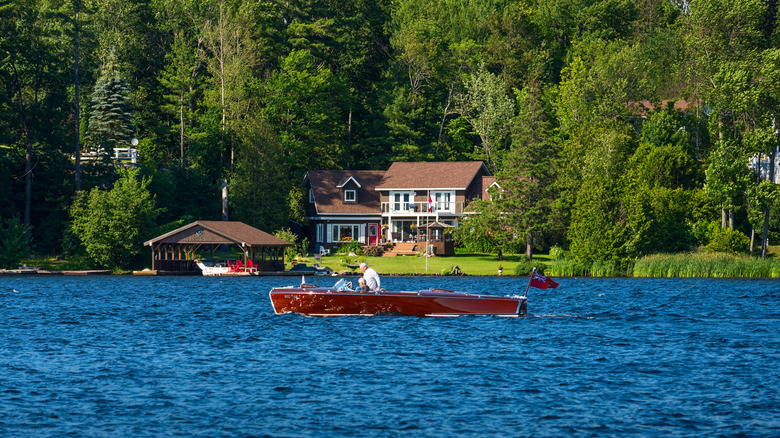A couple in a boat on a lake in the Muskoka region passing a house on the shore