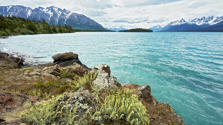 Chilko Lake and its turquoise water, with snow-covered mountains and a cloudy sky as background, British Columbia, Canada