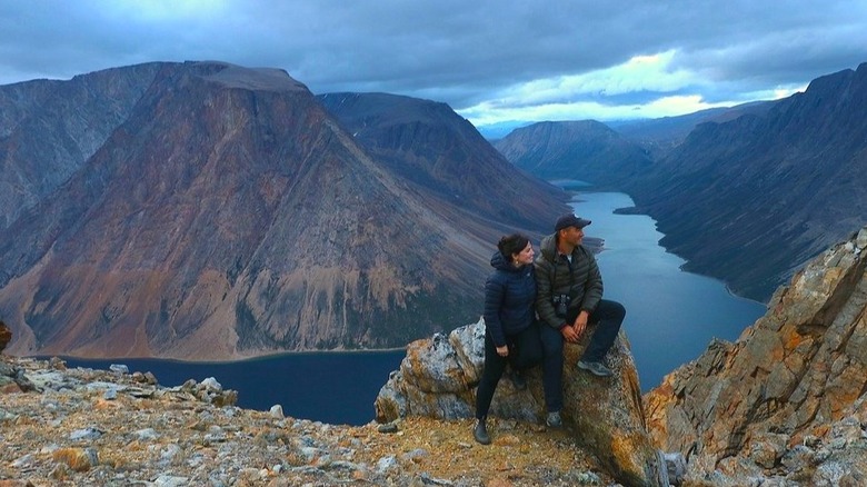 A couple sitting on top of the cliffs of Tuktut Nogait National Park, Northwest Territories