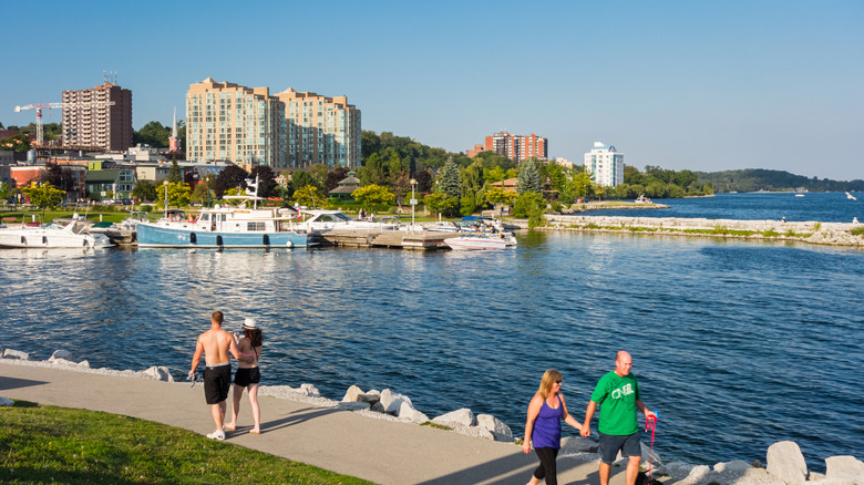 People walking along the waterfront of Lake Simcoe on a bright, clear day in Ontario