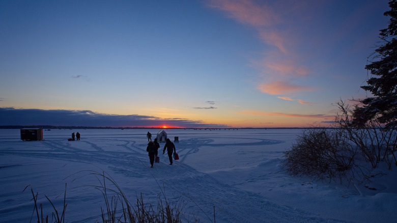A few people ice fishing early in the morning on a frozen Lake Simcoe in the winter