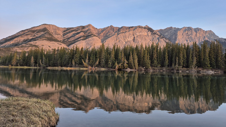 Mountains and trees reflected in the Bow River at Bow Valley Campground