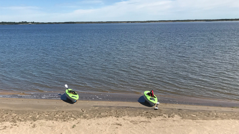 Two green kayaks sitting on a sandy shoreline of Lake Diefenbaker