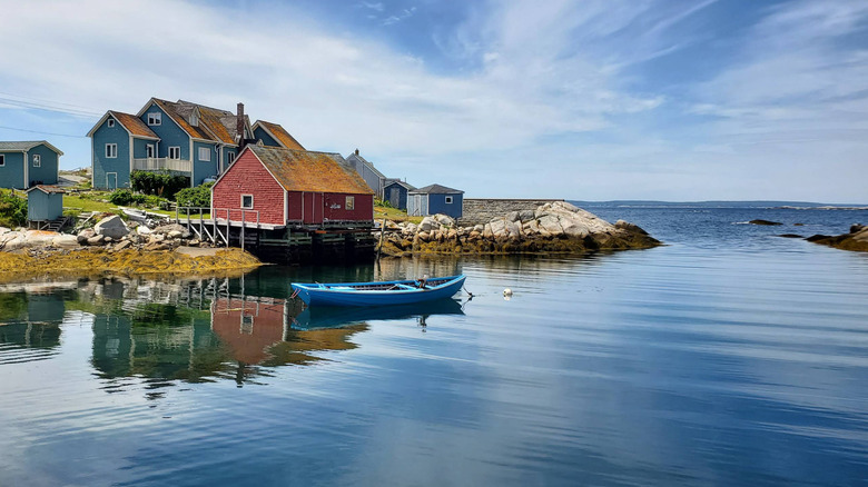 Houses near a mirror still ocean with a kayak in Chester, Canada, with a blue sky full of cirrus clouds