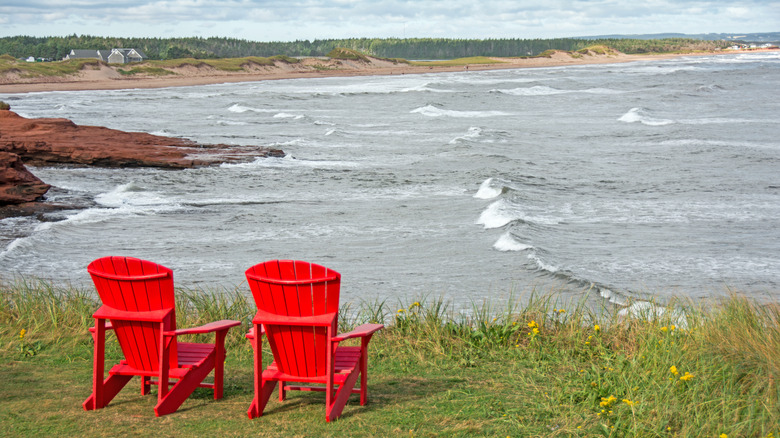 Red Adirondack chairs on the shoreline of Cavendish Beach, Prince Edward Island National Park