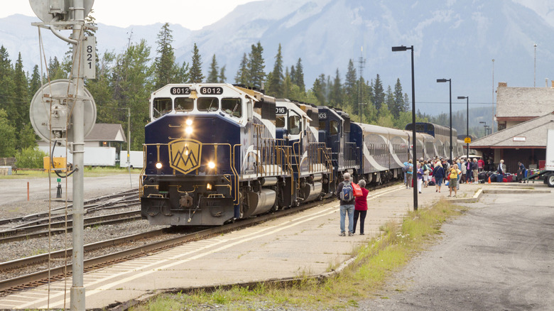 Passengers waiting beside the Rocky Mountaineer train in Banff, Canada