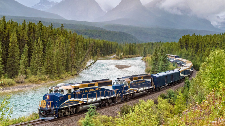Rocky Mountaineer train rounding a bend next to a river in the Canadian Rockies