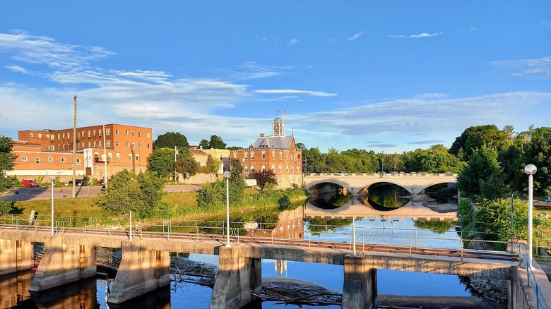 Two bridges straddling the Muskrat River in Pembroke, Ontario, with red brick buildings and trees
