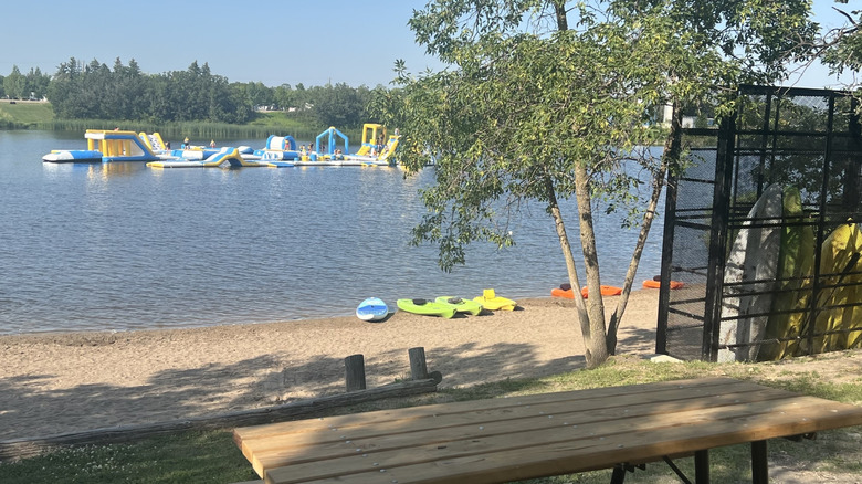 Beachfront with kayaks and inflatable waterpark on Lake Minnewasta in Morden, Canada