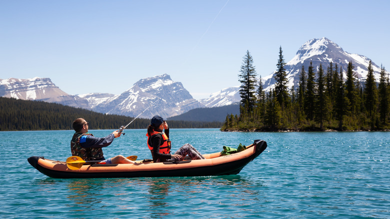 Fishing on a kayak in Banff National Park with snowy mountains in the backdrop