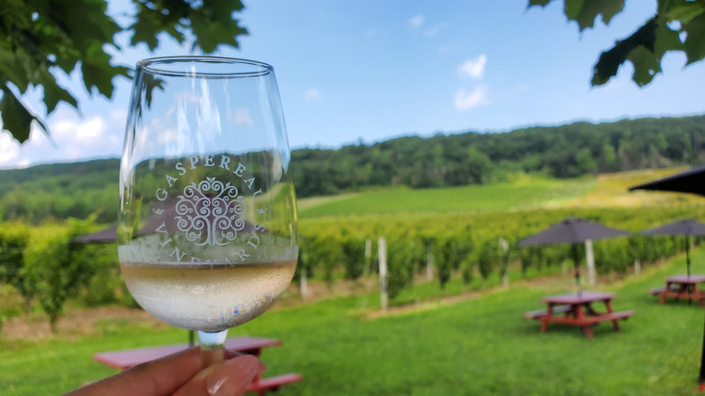 A close-up of a woman's hand holding a glass of white wine at Gaspereau Vineyards in Nova Scotia