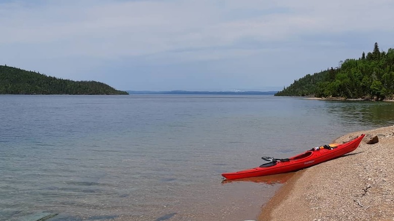 Lone kayak is kept ready on Slate Islands beach by clear waters of Lake Superior