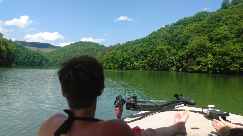 Boaters drifting on the calm, emerald waters of Carr Creek Lake in Kentucky, surrounded by lush hills