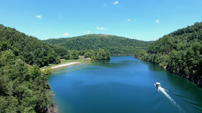 Aeriel views of a boat cruising on Carr Creek Lake in Kentucky, featuring blue waters, surrouned by lush hills