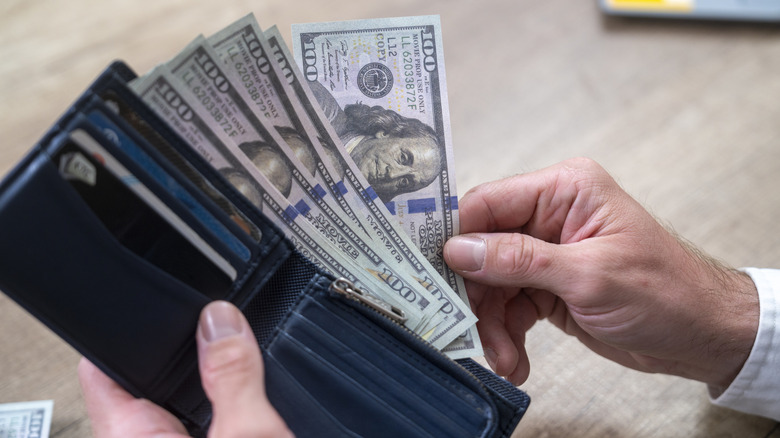 Guy pulling $100 bills out of wallet