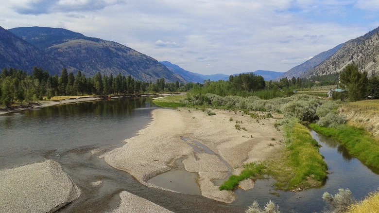 Valley with sand and arid patches of green split by river waters