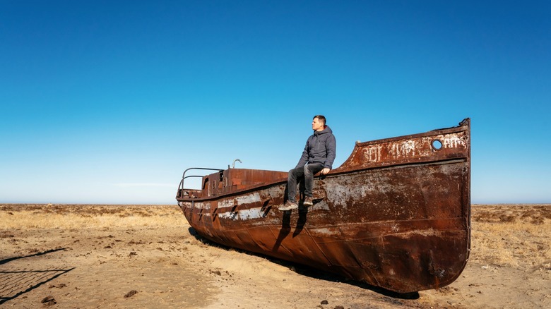 A man sits on an abandoned boat at Bersa-Kelmes