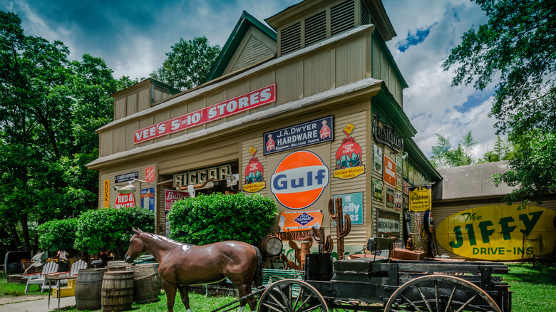 One of the antique shops on Antique Row with tons of unique items in front of it surrounded by bush and trees on a cloudy day in Chamblee, GA