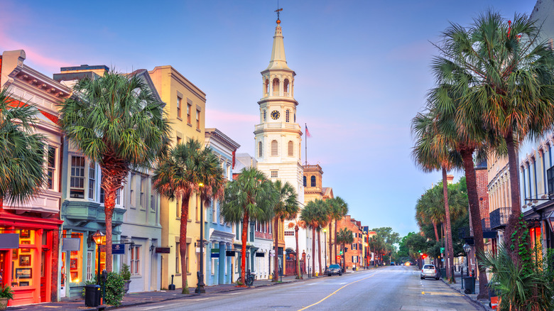 Charleston street lines by colorful buildings and palm trees under blue sky