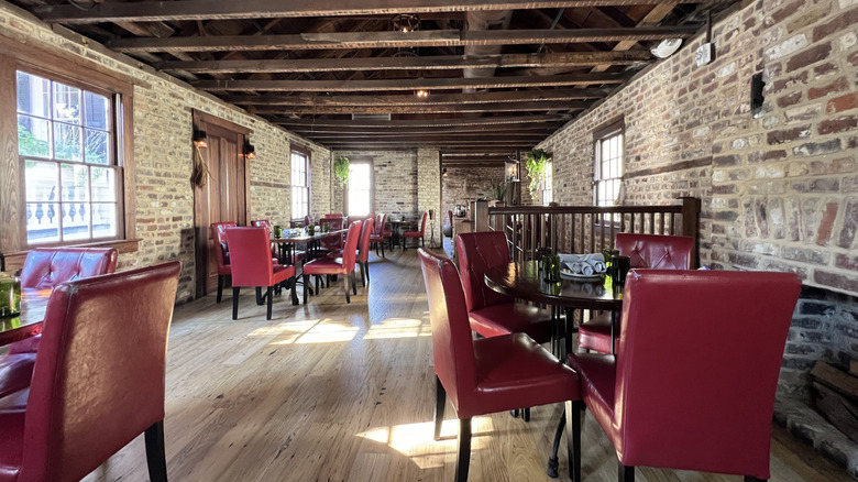 Red chairs at small tables surrounded by brick walls at Husk Charleston