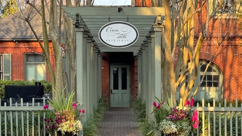 Exterior of Circa 1886 restaurant with sign and green fence