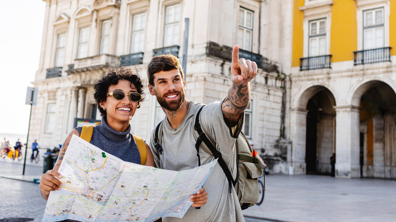 Two people pointing toward something looking at an itinerary