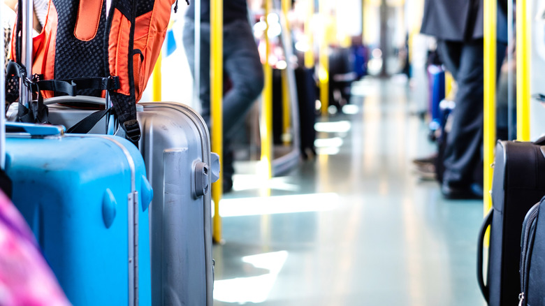 A photo of two large suitcases off to the side of the aisle in a public transit vehicle