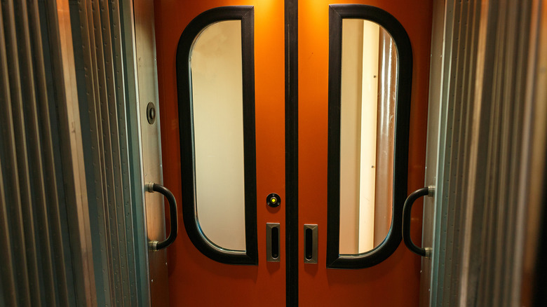 A set of shut orange doors that go between subway train cars