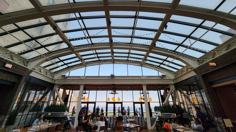 Diner's eating and drinking under a glass roof at Cindy's Rooftop in Chicago