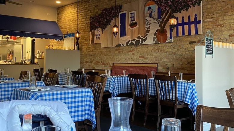 The interior of It's Greek 2 U Grill with tables covered in blue and white gingham tablecloths