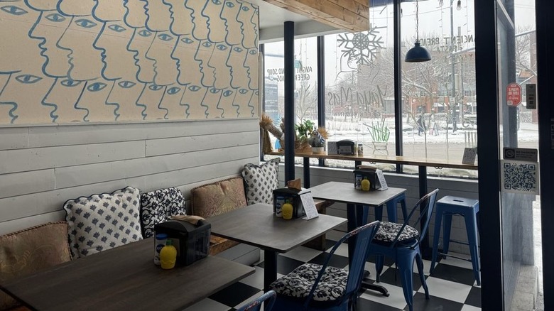 Wooden tables and benches with colorful cushions at Yaya Mas Greek Kuzina in Chicago.