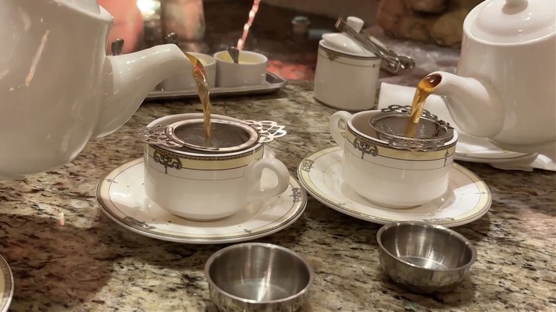Two teapots pouring tea