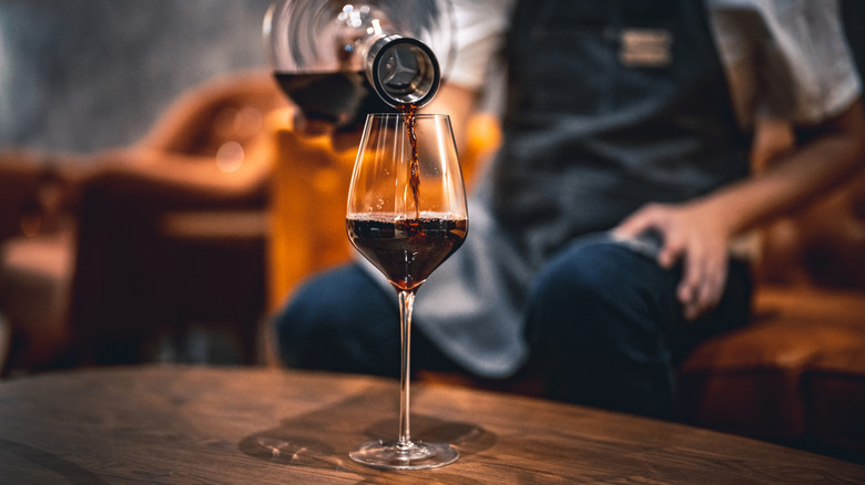Person pouring red wine into a glass