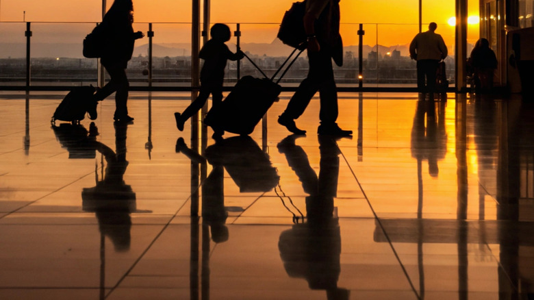 Silhouette of a family walking in an airport as a plane takes off behind them