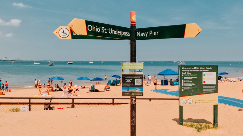 Signs pointing to Chicago attractions with clear beach day background
