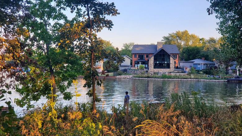 A person standing at the edge of Lake Zurich amidst colorful foliage and trees