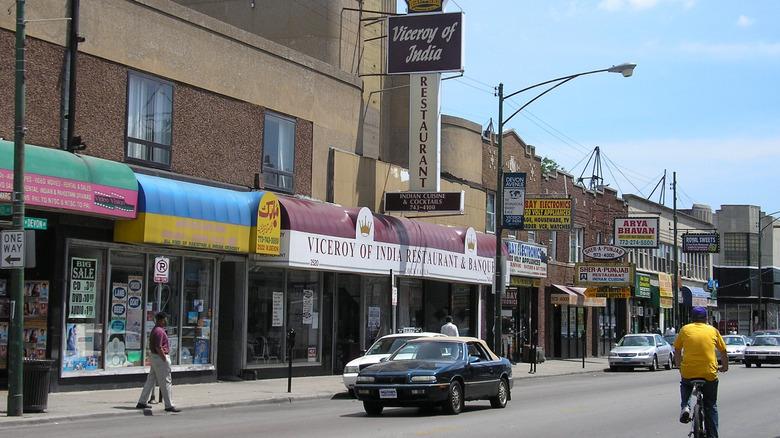 South Asian stores on both sides of Devon Avenue, cars parked on the street.