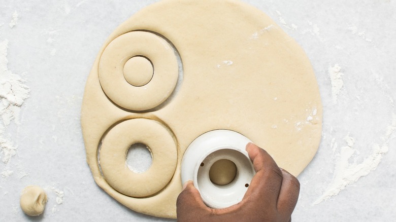 Donut holes being cut out of dough in preparation to make donuts
