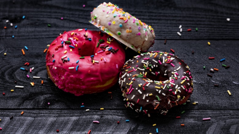 A strawberry, chocolate and birthday cake donut placed together on a table