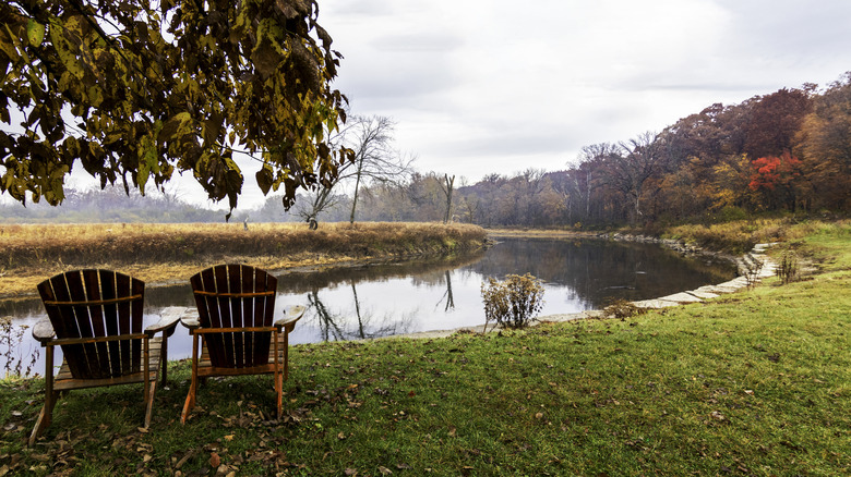 Chairs against river backdrop with woodlands in fall colors