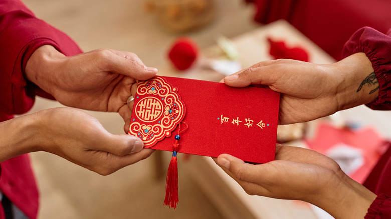 Close-up of receiving a red envelope with two hands during Chinese New Year