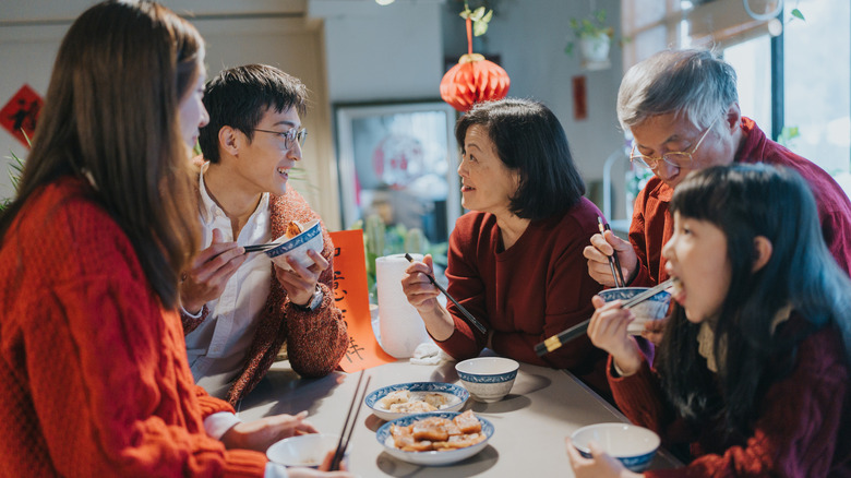 Intergenerational Chinese family talking over bowls of food