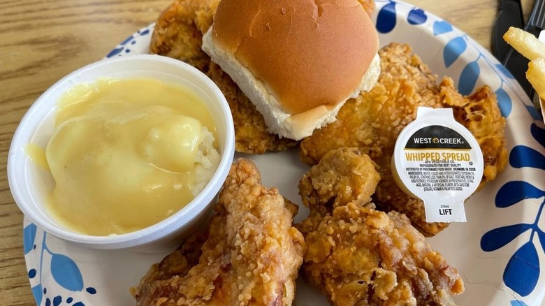 Fried chicken on a plate with mashed potatoes and a roll