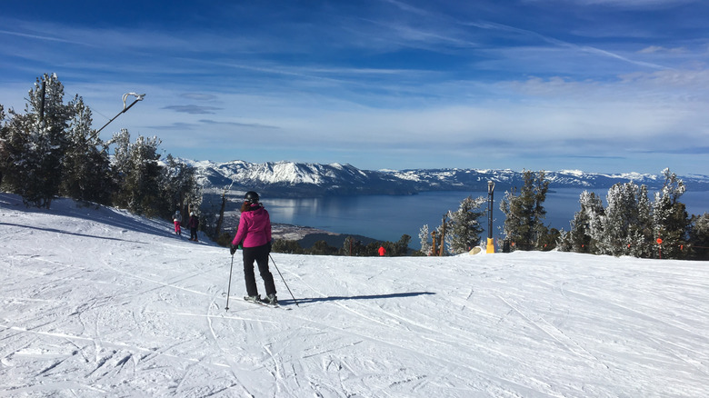 Woman skiing down a slope, enjoying winter sport activity with mountain lake view