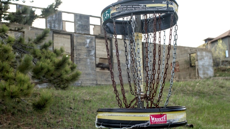 Disc golf basket in front of building ruins